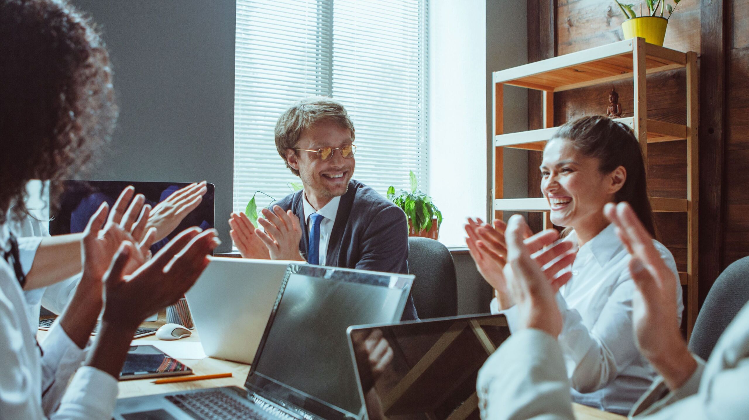 team in a meeting where everyone is clapping and laughing